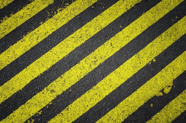 Contrassegni stradali a strisce gialle su strada asfaltata nera. In costruzione
. - Foto, immagini