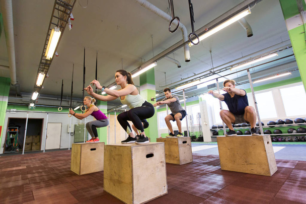 group of people doing box jumps exercise in gym - Foto, Imagem