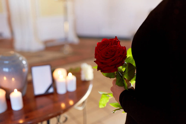 woman with roses and cremation urn at funeral - Foto, afbeelding