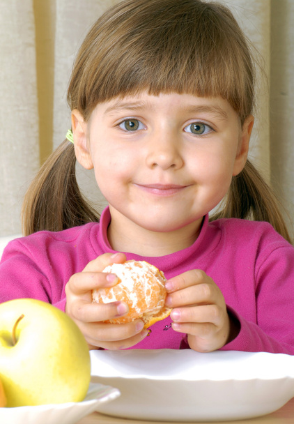 Little girl eating fresh tangerine - Fotó, kép
