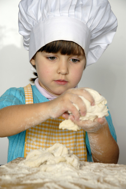 Little girl cooking a pizza in a kitchen.Little kid in a kitchen. - Foto, imagen