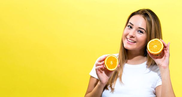 Happy young woman holding oranges halves - Фото, изображение