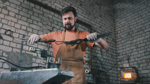 Herrero muscular en forja martilleando productos de acero
 - Foto, imagen