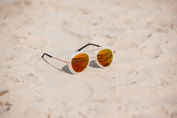 Sunglasses on sandy beach in summer. Vacation background - Foto, imagen