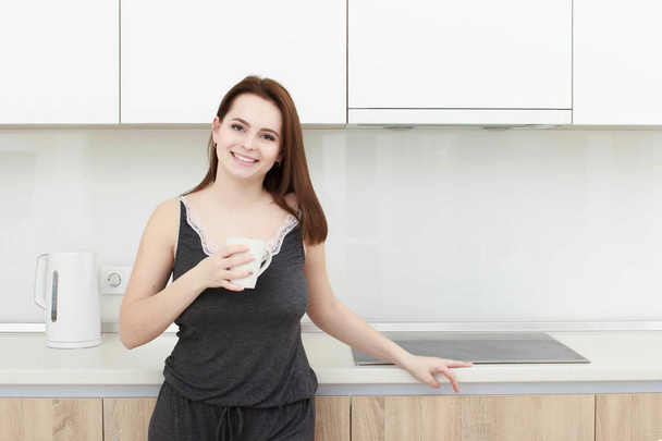 Nuori nainen musta hiusten juominen kahvia keittiössä
 - Valokuva, kuva