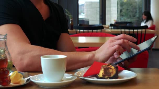 A man in a cafe and works on a tablet - Felvétel, videó