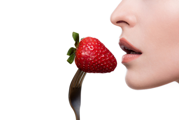 молода жінка їсть полуницю на виделці
 - Фото, зображення