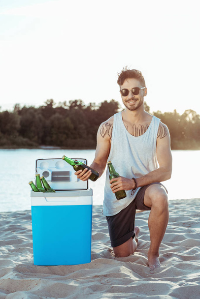 человек берет пиво из переносного холодильника
 - Фото, изображение