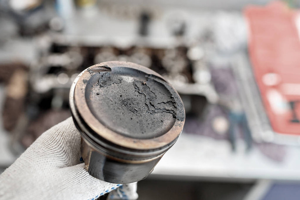 mecánico reparador en los trabajos de reparación de mantenimiento de motores de automóviles. mantener en la mano el pistón con depósitos de carbono
 - Foto, imagen