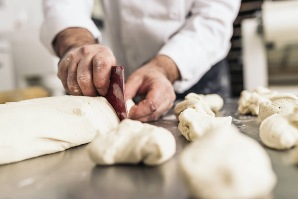 Baker kneading dough in a bakery. - Foto, afbeelding