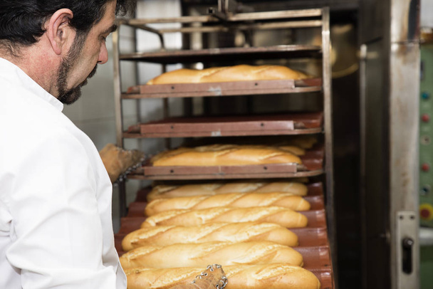 Baker making bread at a bakery. - Foto, Imagen