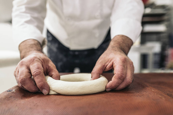 Baker kneading dough in a bakery.  - Фото, изображение