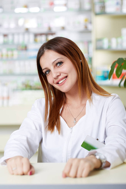 Young pharmacist lady at desk - Фото, изображение