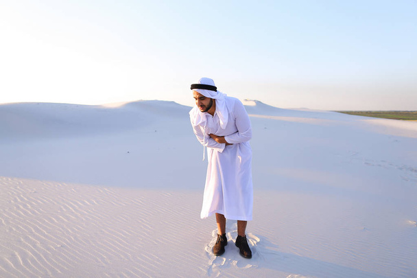 Молодой эмират мужского пола страдает от сильных болей в животе, стоя
 - Фото, изображение
