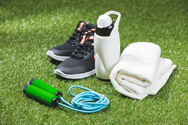 scarpe da ginnastica con bottiglia d'acqua e asciugamano su erba
 - Foto, immagini