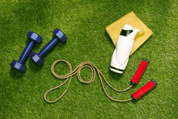 dumbbells and bottle with jump rope on grass - Photo, Image