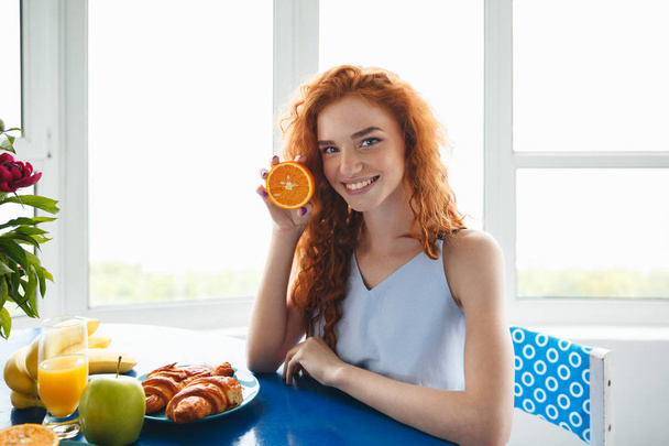 Young smiling redhead lady holding orange - Фото, изображение