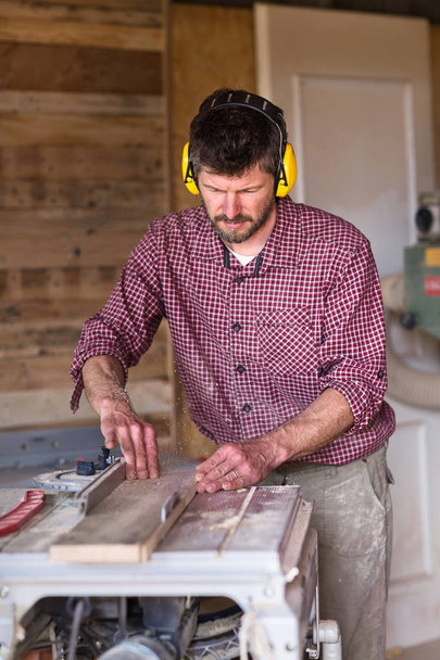 Mannelijke Carpenter snijden plank door cirkelzaag - Foto, afbeelding