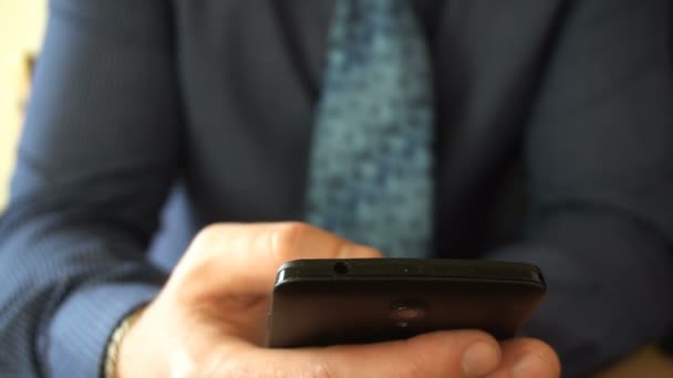 Close-up op een zakenman browsen berichten op zijn laatste generatie smartphone. - Video