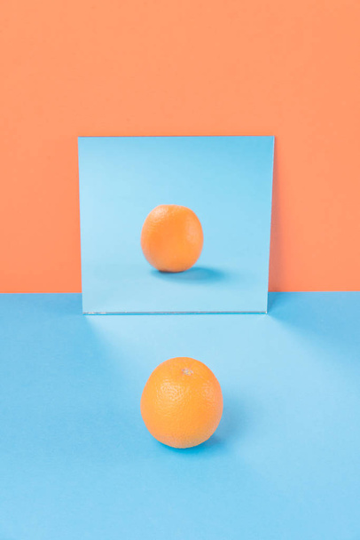 Orange on blue table isolated over orange background - Фото, зображення