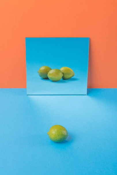 Lime on blue table isolated over orange background - Fotó, kép