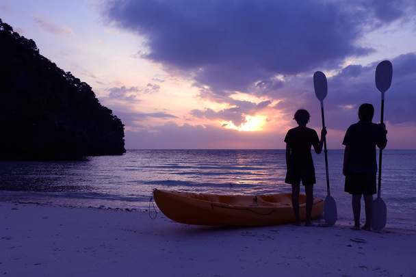 Силуэт каякинга на пляже с туристической девушкой, смотрящей на синее небо заката
. - Фото, изображение