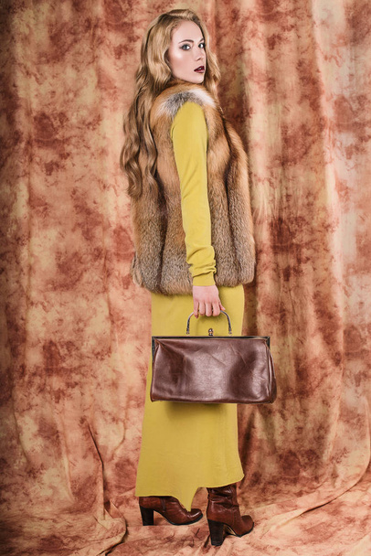 гламурный портрет красивой молодой женщины в меховом жилете с сумкой
 - Фото, изображение