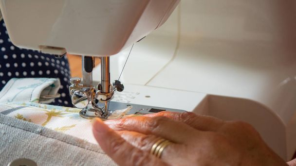 женская рука с помощью швейной машинки сшивания ткани
 - Фото, изображение