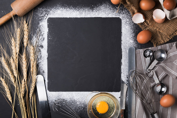 Συστατικά ψησίματος: αυγό και αλεύρι στο μαύρο του σκάφους. - Φωτογραφία, εικόνα