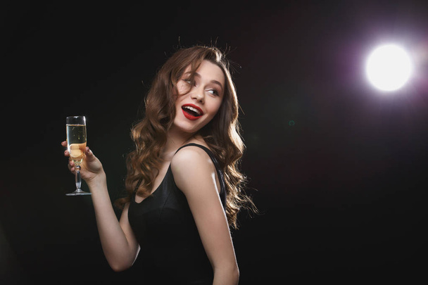 Happy lovely woman with glass of champagne standing and smiling - Foto, Imagen