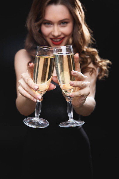 Smiling attractive young woman holding two glasses of champagne - Fotó, kép