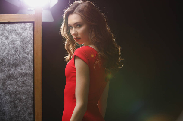 Portrait of beautiful young woman in red dress standing - 写真・画像