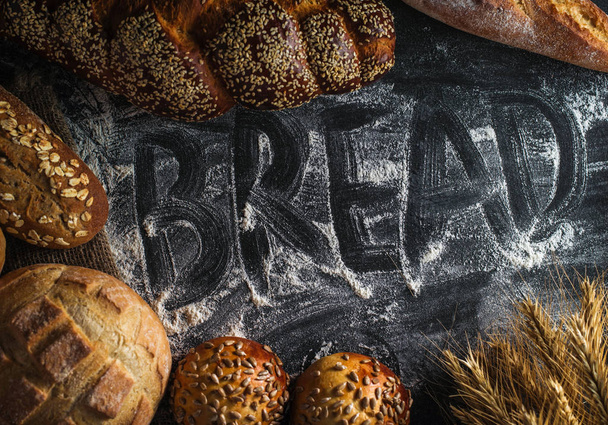Background with fresh bread and inscription "Bread" on flour - Valokuva, kuva