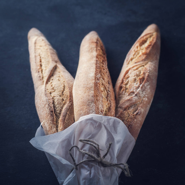 Three freshly baked baguettes on the table. - Фото, изображение