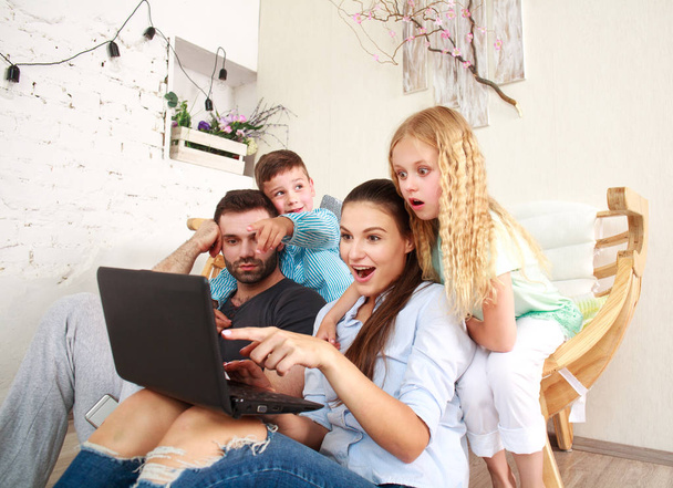 Happy family with two kids at home looking fun on laptop - Fotoğraf, Görsel
