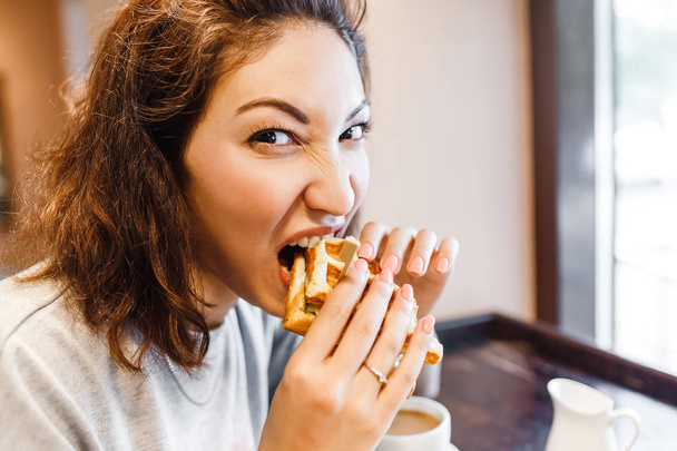 Mujer del Este comiendo sándwich en el interior de la cafetería
 - Foto, imagen