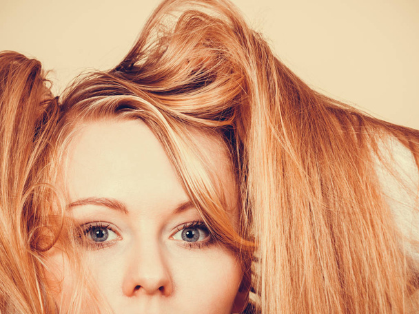 Blonde woman holding her long tangled hair - Foto, imagen