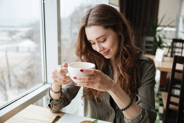 Cute cheerful young beautiful lady sitting in cafe drinking tea. - Photo, Image