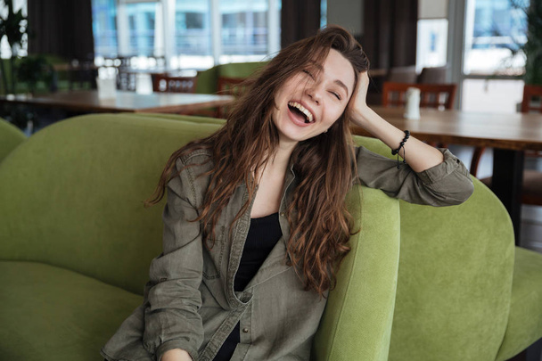 Mujer sonriendo mientras se sienta en la cafetería
 - Foto, imagen