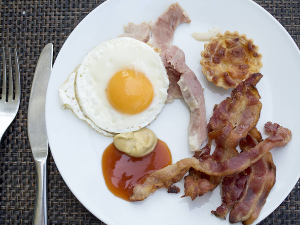 Desayuno, huevos fritos, salchichas y tocino, acompañados de sol, plano a
 - Foto, Imagen