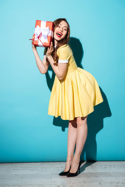Happy young brunette woman holding gift. - 写真・画像