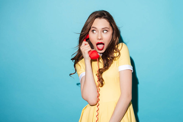 Attractive young girl in dress talking on retro telephone tube - Photo, image