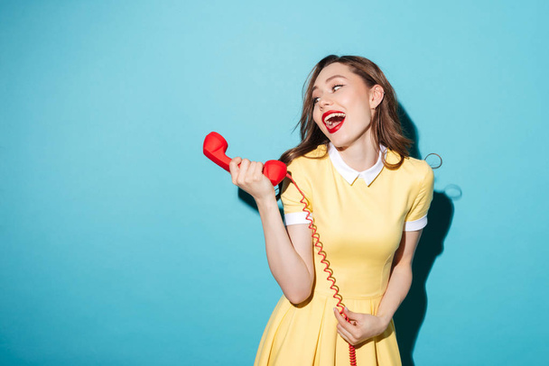 Attractive young girl in dress talking on retro telephone tube - Foto, Bild