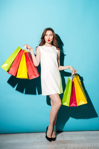 Pretty young brunette woman holding shopping bags. - Фото, изображение