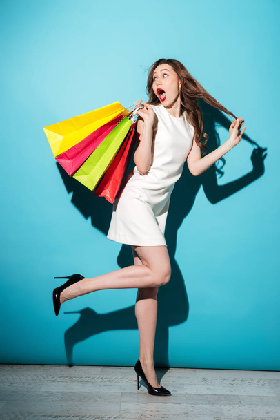 Mujer sonriente en vestido caminando con coloridas bolsas de compras
 - Foto, Imagen