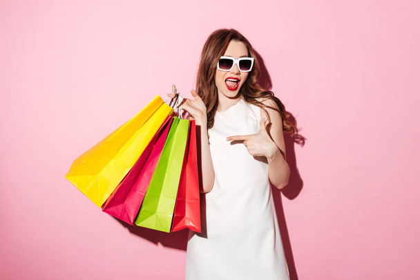 Amazing young brunette woman with shopping bags pointing. - Φωτογραφία, εικόνα