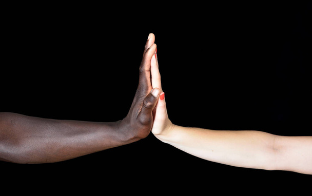 Egy fekete férfi és fekete háttér fehér nő kezében - Fotó, kép