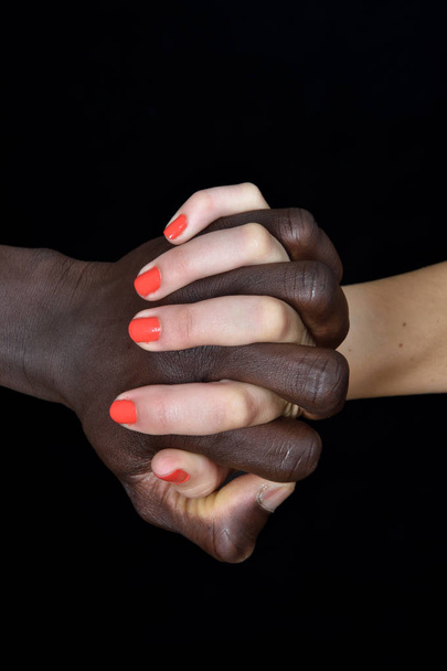 Siyah erkek ve beyaz kadın siyah arka plan üzerine bir el - Fotoğraf, Görsel