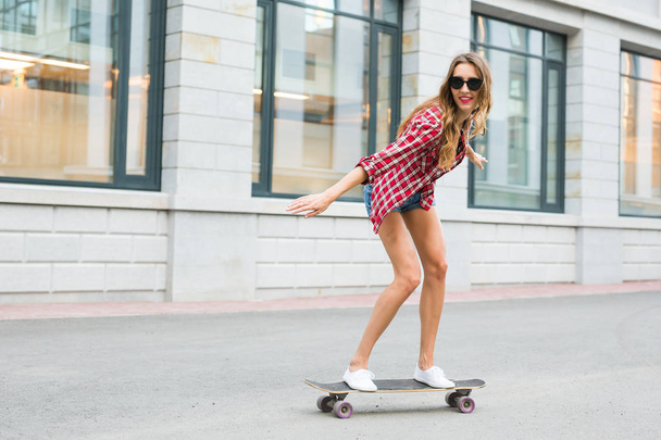 summer holidays, extreme sport and people concept - happy girl riding skateboard on city street - Photo, Image