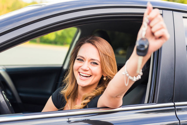 Молода щаслива жінка в машині з ключами в руці концепція купівлі автомобіля
. - Фото, зображення